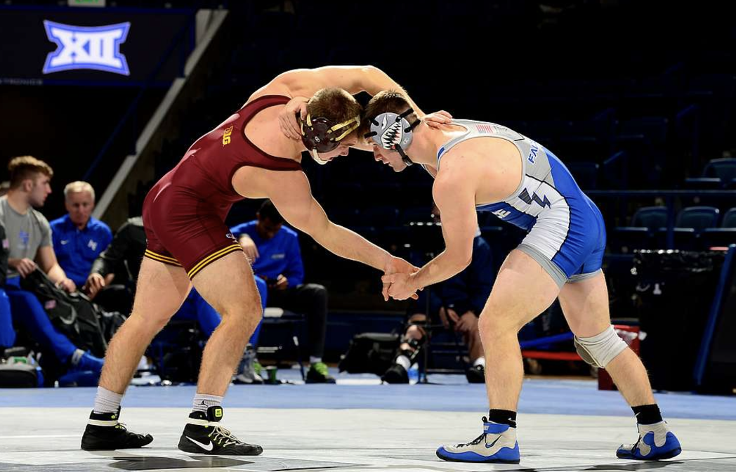 Two men from Minnesota and Air Force wrestling. 